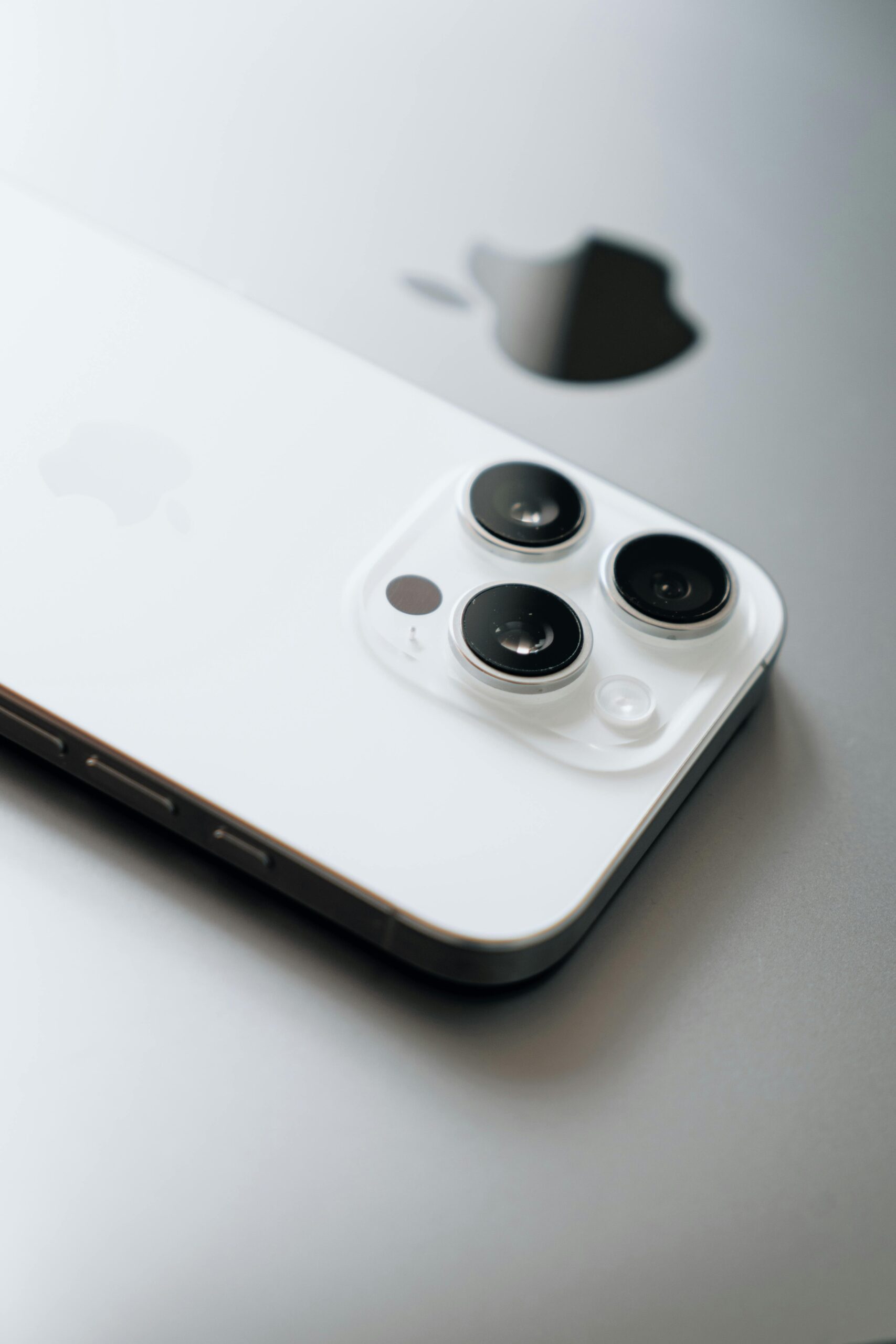 White smartphone with triple cameras lies atop a sleek laptop.